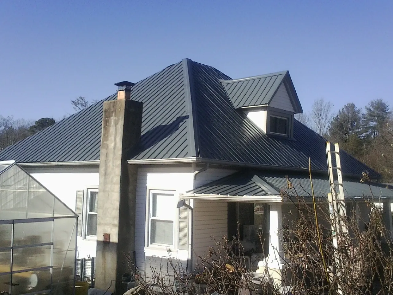 Dark blue standing seam metal roof on a white farmhouse with dormer — Slate & Tile Roof Repair by Roofing Brothers in West Lafayette
