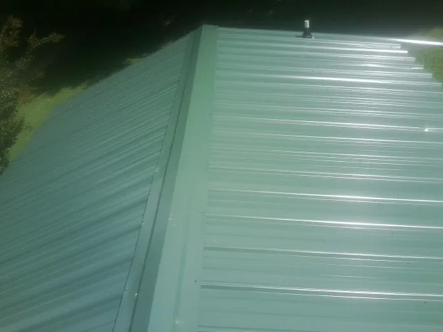 New green metal panels meeting at the ridge of a roof — Flat Roof Repair work by our crew in West Lafayette
