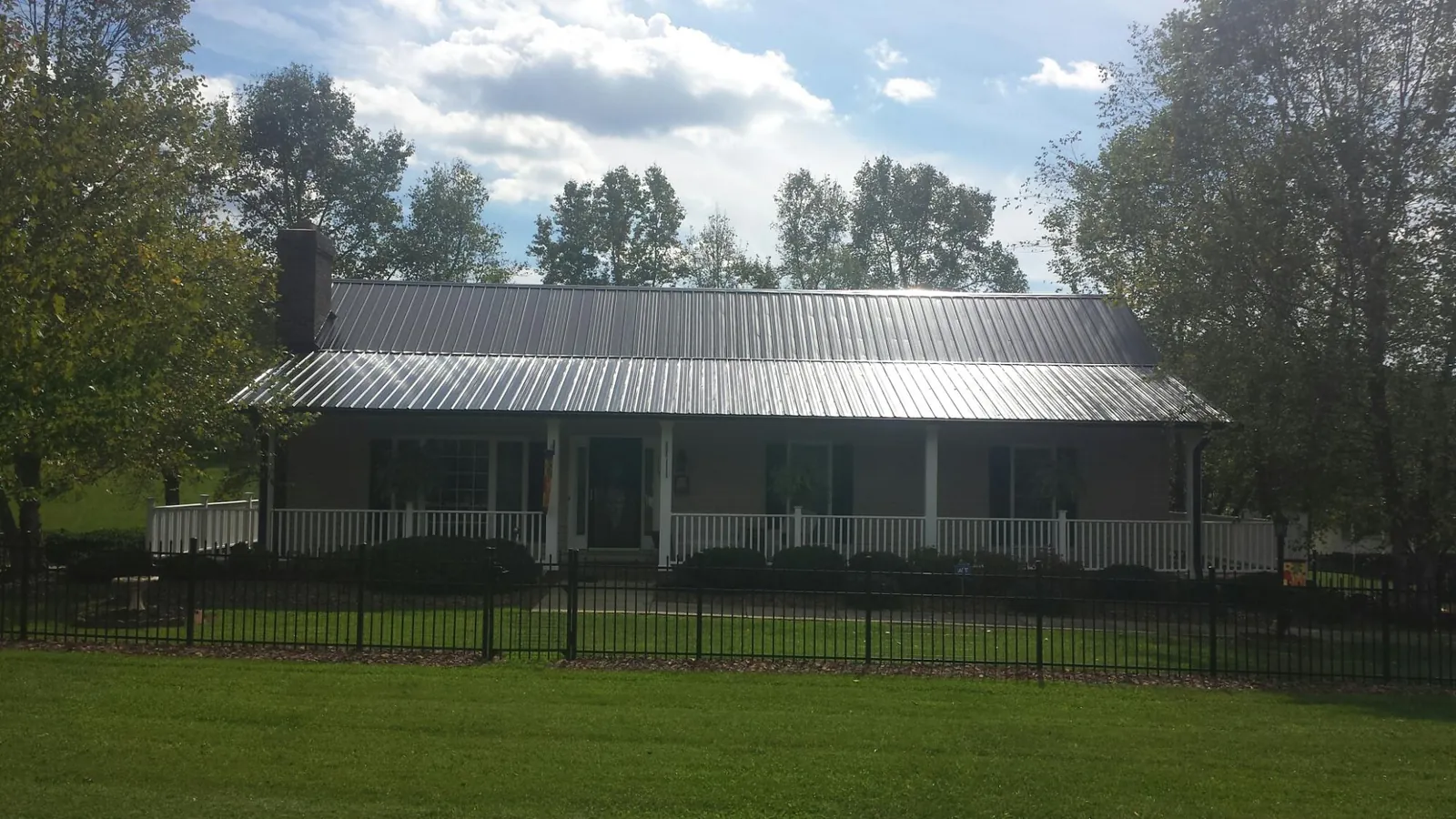 Gray metal roof on a brick ranch with a full width front porch — Gutter Guard Installation work by our crew in West Lafayette