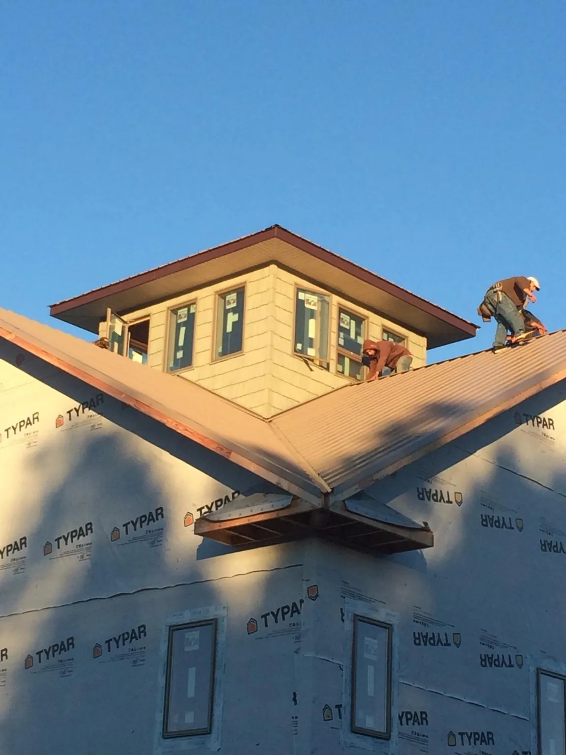 Roofers working around a rooftop cupola on a new metal roof at sunset — Roof Waterproofing in West Lafayette by Roofing Brothers